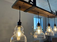 three clear glass pendant lights hanging from a wooden beam