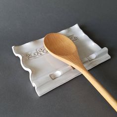 a wooden spoon sitting on top of a white plate with an ice tray underneath it