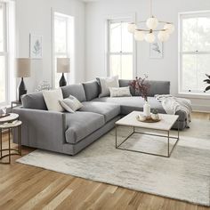 a living room filled with lots of furniture next to two windows and a rug on the floor