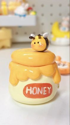 a honey jar sitting on top of a table next to other small toys and figurines