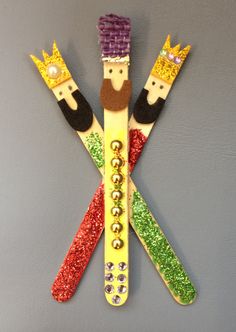 three wooden skis decorated with different colored glitters and crowns on top of each other