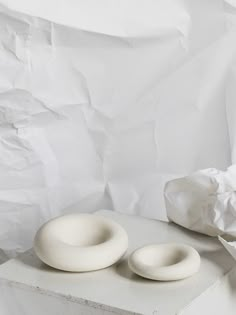 two white ceramic objects sitting on top of a table next to a crumpled paper bag