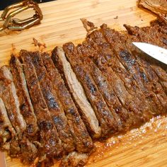 the steak is sliced and ready to be served on the cutting board with a knife