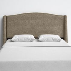 an upholstered headboard with white pillows and linens on a beige bed