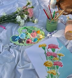 an art project is being displayed on a table with flowers and paintbrushes in it