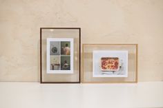 two framed pictures are on a shelf next to each other, one with a pizza in it