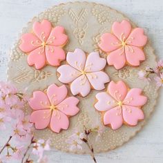 decorated cookies with pink and yellow flowers on a doily next to some cherry blossoms