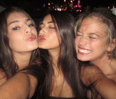 three beautiful young women sitting next to each other in the back seat of a car