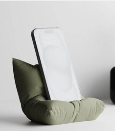 a cell phone sitting on top of a pillow in the shape of an armrest