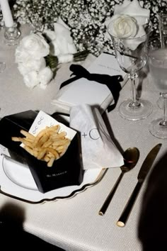 the table is set with white flowers and silverware