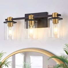 three light bathroom fixture with clear glass shades and gold accents on the wall above it