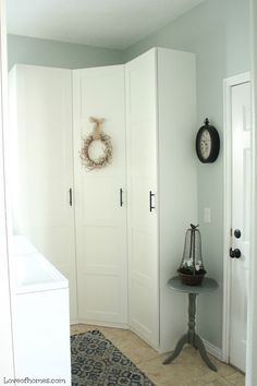 a room with white doors and a clock on the wall next to a small table