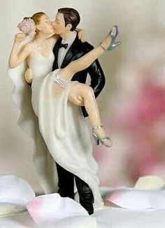 a figurine of a bride and groom kissing on the cheek with petals around them