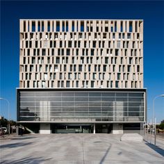 an empty parking lot in front of a tall building with lots of windows on it