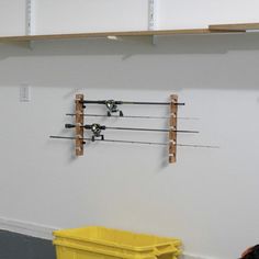 two fishing rods are hanging on the wall next to a yellow trash can and bin