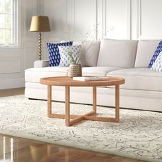 a living room with white couches and blue pillows on the table in front of it