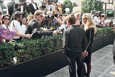 a group of people standing next to each other in front of a fence with cameras