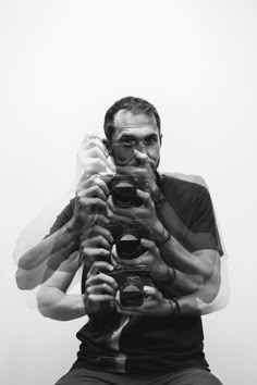 a man sitting down holding a camera up to his face and taking a selfie