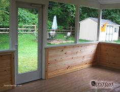 an enclosed porch with sliding glass doors and wood flooring on both sides, looking out onto the back yard