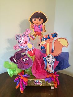 dora the explorer centerpiece with cutouts and tissue pom poms on a wooden table