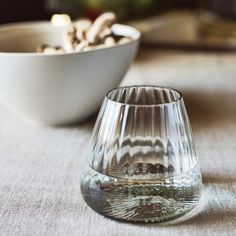 an empty glass sitting on top of a table next to a bowl