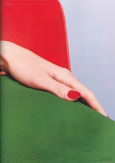 a woman's hand resting on the back of a green chair with red nail polish