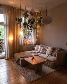 a living room filled with lots of furniture and plants hanging from the ceiling above it