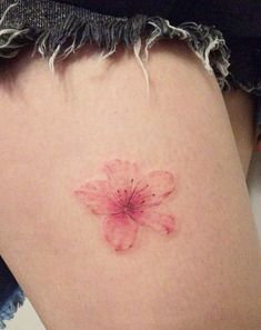 a small pink flower on the back of a woman's thigh