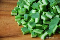 chopped up green vegetables sitting on top of a wooden cutting board