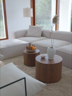 a living room filled with white furniture and large windows overlooking the trees in the distance