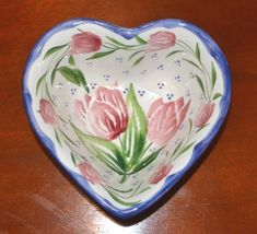 a heart shaped bowl with flowers painted on it