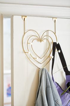 a pair of jeans hanging on a hook next to a heart - shaped coat rack