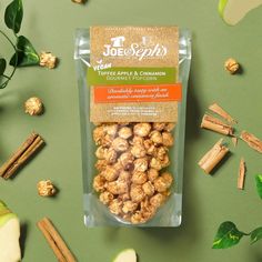 a bag of apple and cinnamon gourmet popcorn on a green surface with apples around it