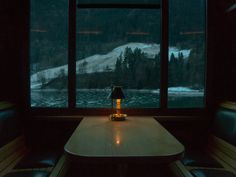 a table with a lamp on it in front of a window that looks out over the water