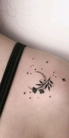 the back of a woman's shoulder with stars and leaves tattoo on her left side