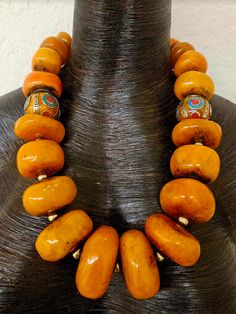 This exotic and wild Berber Style Moroccan Resin tribal statement necklace is an awesome piece for either a man or woman. These huge, bold and chunky Moroccan Resin beads have the look of the real organic amber without the price. The largest bead measures approximately 2" while the smallest measures approximately 1". Each has a shiny gold tone metal ball spacer. There are two Tibetan resin accent beads inlaid with brass, turquoise and coral. The back is finished with Chinese brass coins and ornate gold beads. Adjusts from 24-27" and I can add more links if requested. Gold tone hardware, lobster clasp and a 3" extender complete the piece. Stunning worn alone or layered copper, coral or turquoise. An ethnic, haute couture unisex piece from the Atelier of Kat Kouture. Has a strong street styl Luxury Unique Jewelry With Round Beads, Luxury Polished Beads For Festivals, Luxury Bohemian Beaded Necklaces With Bead Caps, Luxury Beaded Necklaces With Round Beads For Festivals, Luxury Round Bead Necklaces For Festivals, Luxury Round Beads Necklaces For Festivals, Luxury Colorful Round Beaded Jewelry, Luxury Artisan Beaded Necklaces With Round Beads, Boho Statement Necklace Unique Statement Jewelry By Bling Beaded Baubles