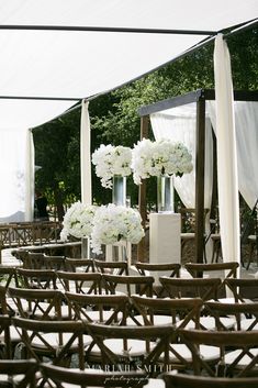 rows of chairs with white flowers in vases on the back and sides, set up for an outdoor wedding ceremony