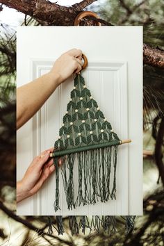 a person is holding a piece of fabric in front of a door with a green triangle on it