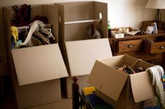 two cardboard boxes are stacked on top of each other in a room with clutter