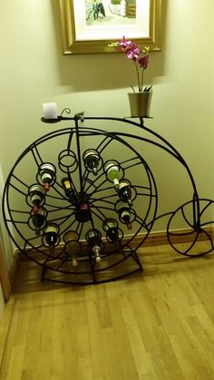 a metal wine rack sitting on top of a hard wood floor next to a wall