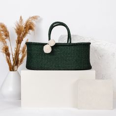 a green purse sitting on top of a table next to a white vase and plant