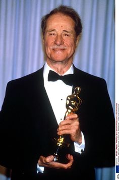 an older man in a tuxedo holding his oscar award