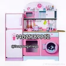 a pink toy kitchen with lots of appliances on it's shelves and cupboards