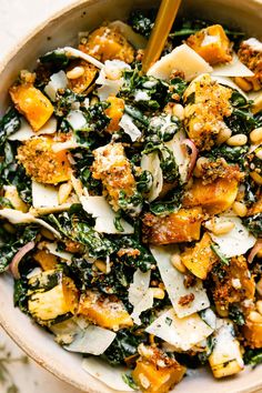 a bowl filled with pasta, spinach and other toppings next to a wooden spoon