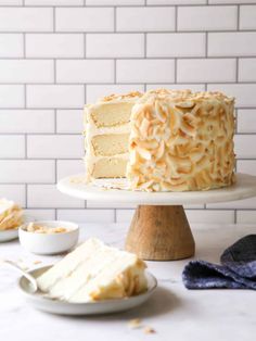 a white cake sitting on top of a table next to two plates with slices of cake