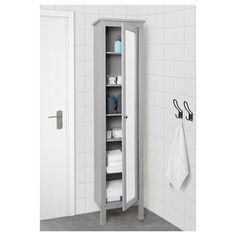 a white bathroom with a tall cabinet in the corner