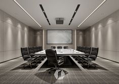 an empty conference room with black chairs and a large screen on the wall above it