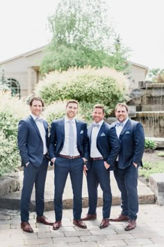 a group of men in suits standing next to each other on a brick floored walkway