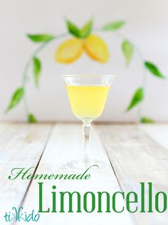 a glass filled with yellow liquid sitting on top of a wooden table