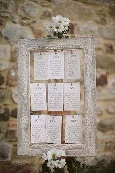 an old frame with seating cards attached to it and flowers in the middle on top